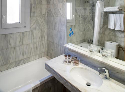 a white bathroom with a sink and a bath tub at Catalonia Castellnou in Barcelona