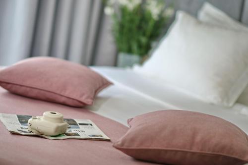 a bed with two pink pillows and a bottle on it at City Nest Modern & Cozy Suites in Belgrade
