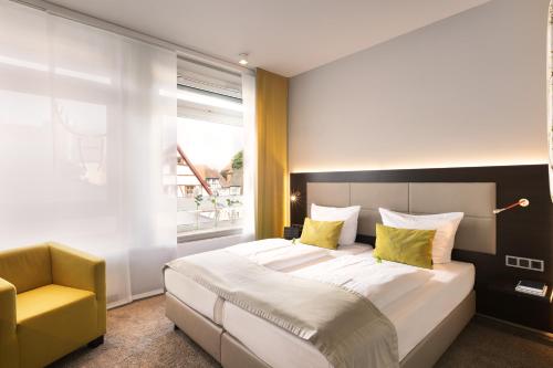 a bedroom with a large bed and a yellow chair at Hotel Platzhirsch in Fulda