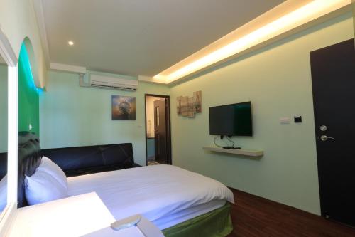 a bedroom with a bed and a flat screen tv at Amir B&B train station & elevator with parking lot in Hualien City