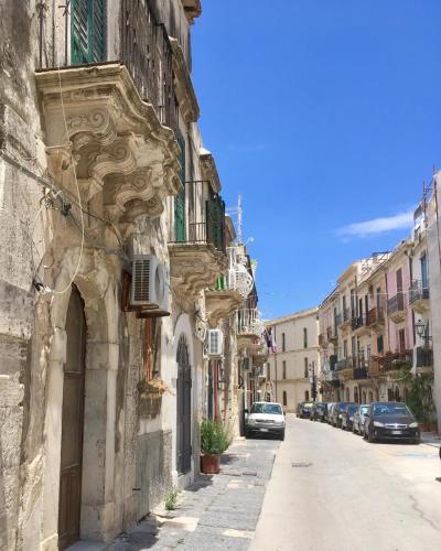 an old stone building with cars parked on a street at La Casa del mare in Syracuse