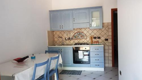 una cocina con armarios azules y una mesa con sillas en villa del maestro, en Lenola