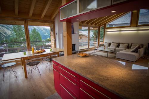 a kitchen with red cabinets and a living room with a couch at Chalet Sperling in Saas-Fee