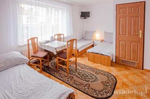 ブワディスワボボにあるPokoje Monikaのテーブル、椅子、ベッドが備わる客室です。