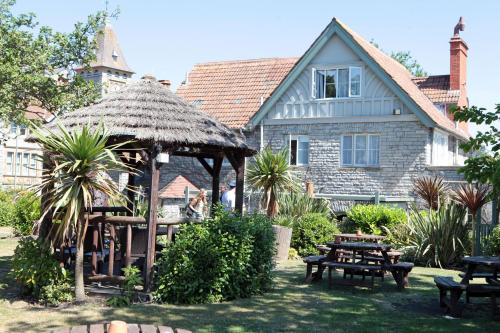 a house with a gazebo and picnic tables in the yard at Bear Inn, Somerset by Marston's Inns in Street