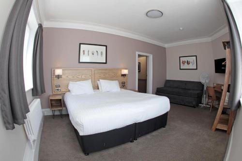 a bedroom with a large white bed and a couch at Bear Inn, Somerset by Marston's Inns in Street