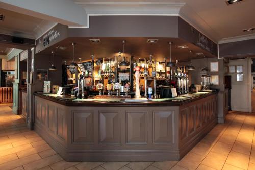 a bar in a pub with a lot of alcohol at Bear Inn, Somerset by Marston's Inns in Street