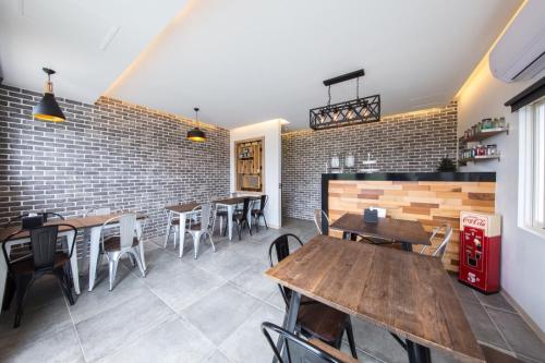 a restaurant with wooden tables and chairs and a brick wall at Tiffany Homestay in Eluan