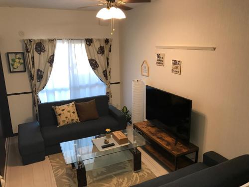 een woonkamer met een bank en een tv bij EX Itoman Apartment 802 in Itoman