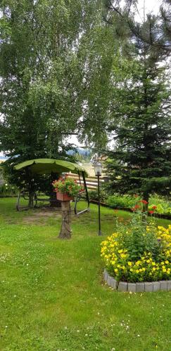 a park with a tree and flowers in the grass at Noclegi Barbara in Czorsztyn