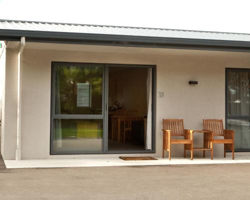 two chairs and a table in front of a house at Grove Park Motor Lodge in Blenheim