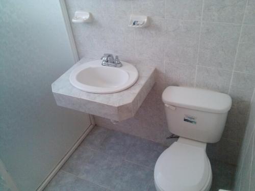 a bathroom with a white toilet and a sink at Cabañas Los Portales Barrancas del Cobre in Areponapuchi