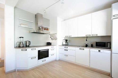 a white kitchen with white cabinets and a wooden floor at Design Apartments Kristiina in Naantali