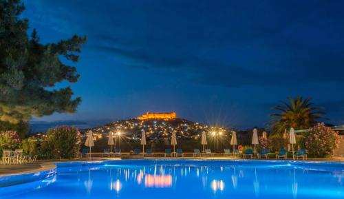 a resort with a large swimming pool at night at Delfinia Hotel & Bungalows in Mithymna