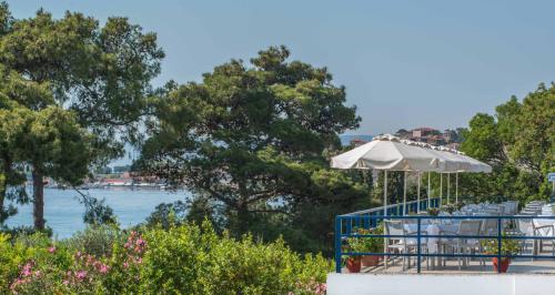 a table with an umbrella and chairs next to the water at Delfinia Hotel & Bungalows in Mithymna