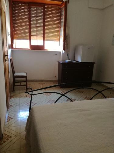 a bedroom with a bed and a chair and a window at Lucapannune in Tricase