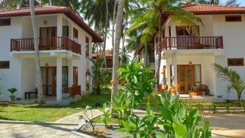 a white house with palm trees in front of it at Good Karma in Tangalle