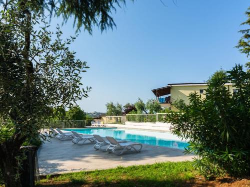 MontinelleにあるSecluded Apartment in Manerba del Garda with 3 Poolsのラウンジチェア付きのスイミングプールが隣接しています。