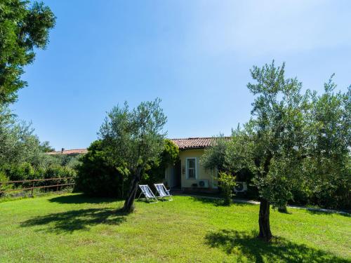 MontinelleにあるSecluded Apartment in Manerba del Garda with 3 Poolsの庭に二本の椅子と二本の木がある家