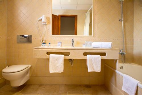 ein Badezimmer mit einem Waschbecken, einem WC und einem Spiegel in der Unterkunft Hotel Antonio in Zahara de los Atunes