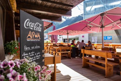 ein Restaurant mit Tischen, Bänken und Sonnenschirmen in der Unterkunft Hôtel Alpina - Swiss Ski & Bike Lodge Grimentz in Grimentz