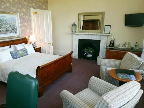 a bedroom with a bed and chairs and a fireplace at Mansfield House Hotel in Hawick