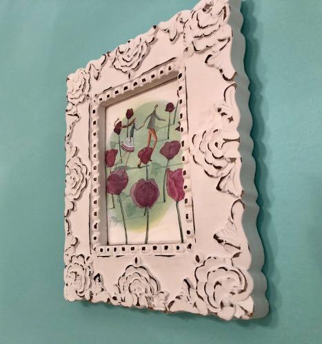 a pink picture frame with red flowers on a wall at B&B Mariupol in Trapani