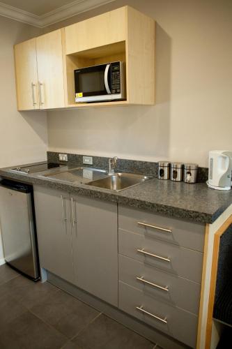 a kitchen with a sink and a microwave at Grove Park Motor Lodge in Blenheim