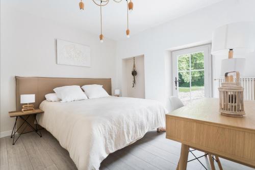 a white bedroom with a large bed and a table at Le moulin des Sens - SPA-SAUNA in Orthez