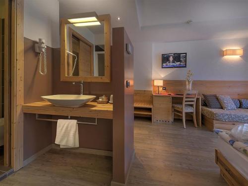 a bathroom with a sink and a bed and a mirror at Hotel Negritella in Folgarida
