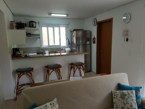 a living room with a couch and a kitchen with stools at Linda Casa em Juquehy in Juquei