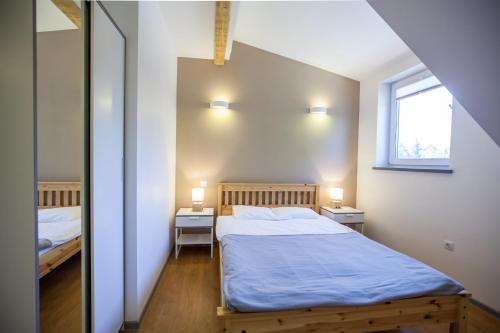 a bedroom with a bed with blue sheets and a window at Namelis Preiloje in Neringa