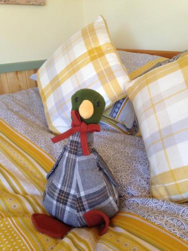 a stuffed teddy bear sitting on a bed with pillows at Lizzie off grid Shepherds Hut The Buteland Stop in Bellingham