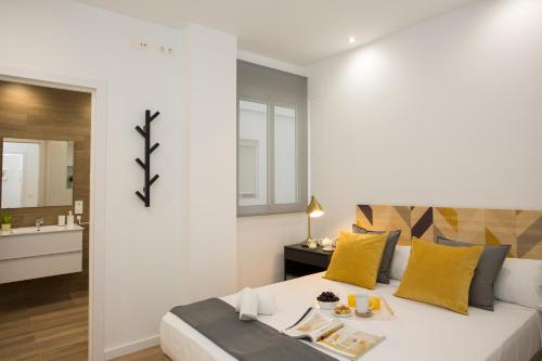 a bedroom with a white bed with yellow pillows at SingularStays Sorolla in Valencia