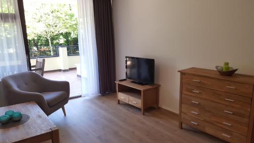 a living room with a television and a dresser with a chair at Appartementhaus Wimmerhof in Bad Füssing