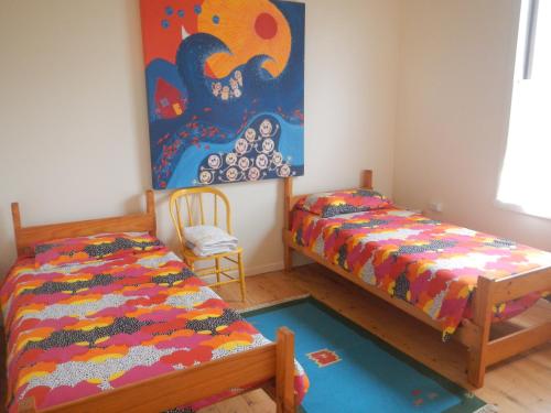 een slaapkamer met 2 bedden en een schilderij aan de muur bij Yarram Cottage: Art and Accommodation in Yarram