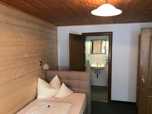 a bed with white pillows in a room with a sink at Zum Kirchenbauer in Oberammergau