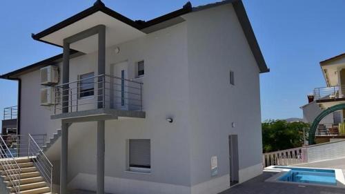 Cette maison blanche dispose d'un balcon et d'une piscine. dans l'établissement Apartments Bilobrk, à Trogir