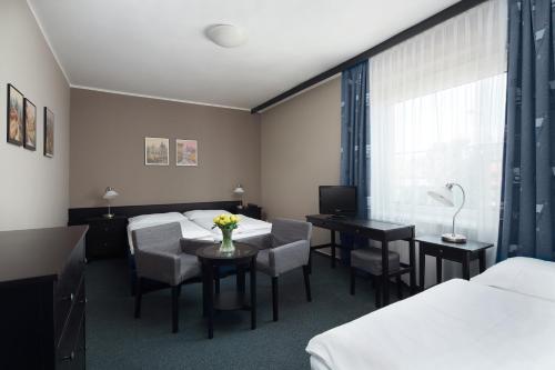 a hotel room with two beds and a table and chairs at Hotel Tulipan Pruhonice in Prŭhonice