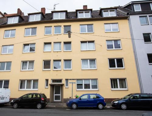 a yellow building with cars parked in front of it at AVR Apartment Geestemunde in Bremerhaven