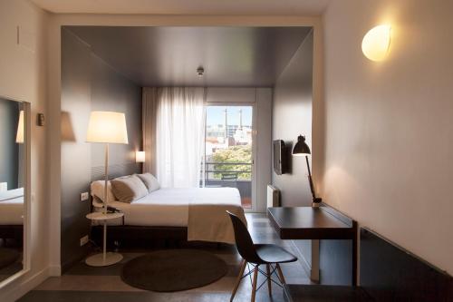 a bedroom with a bed and a desk and a window at Sixties Ramblas in Barcelona