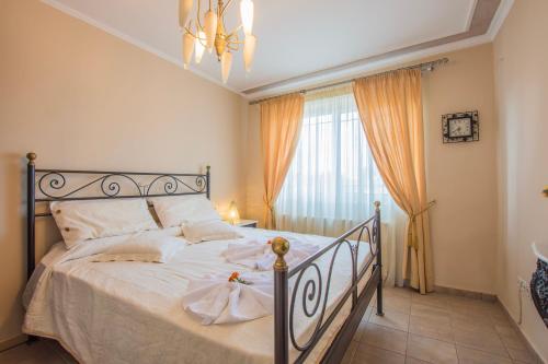 a bedroom with a bed with white sheets and a window at Zante View (4bedroom luxury home) Free Pickup in Zakynthos Town