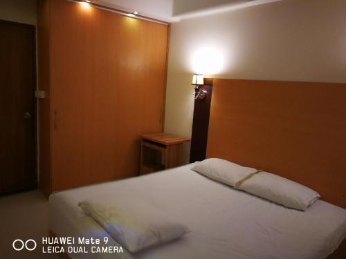 Rajanigandha Family Suites في داكا: غرفة نوم بسرير أبيض مع اللوح الخشبي