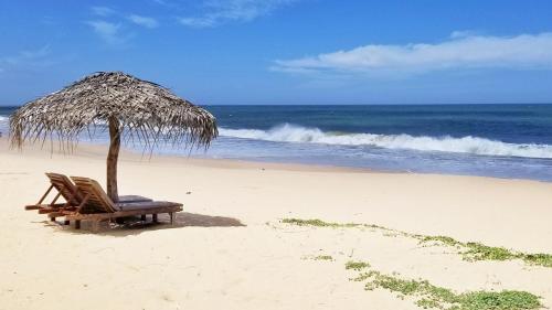 a chair and an umbrella on a beach at Good Karma in Tangalle