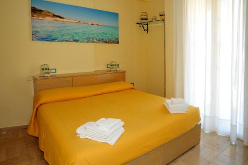 a bedroom with a yellow bed with towels on it at Cala Dei Normanni - Camere sulle Mura in Otranto