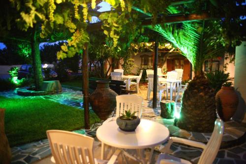 a patio with white chairs and tables and trees at Dimitra Studios in Kastraki Naxou