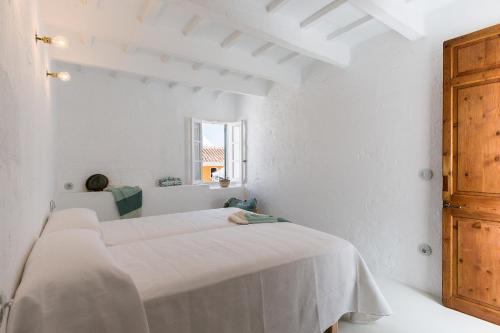 a white room with two beds and a window at Ses Voltes Sant Antoni in Ciutadella