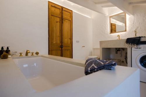 a white bathroom with a tub and a sink at Ses Voltes Sant Antoni in Ciutadella