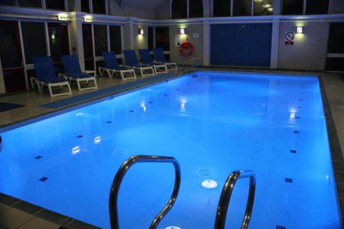 a large swimming pool with blue lighting in a building at Pendley Manor in Tring
