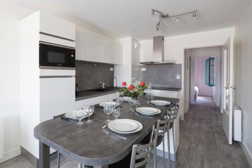 une cuisine avec une table avec des assiettes et des verres à vin dans l'établissement Au Quai Des Pecheurs by Cocoonr, à Saint-Malo